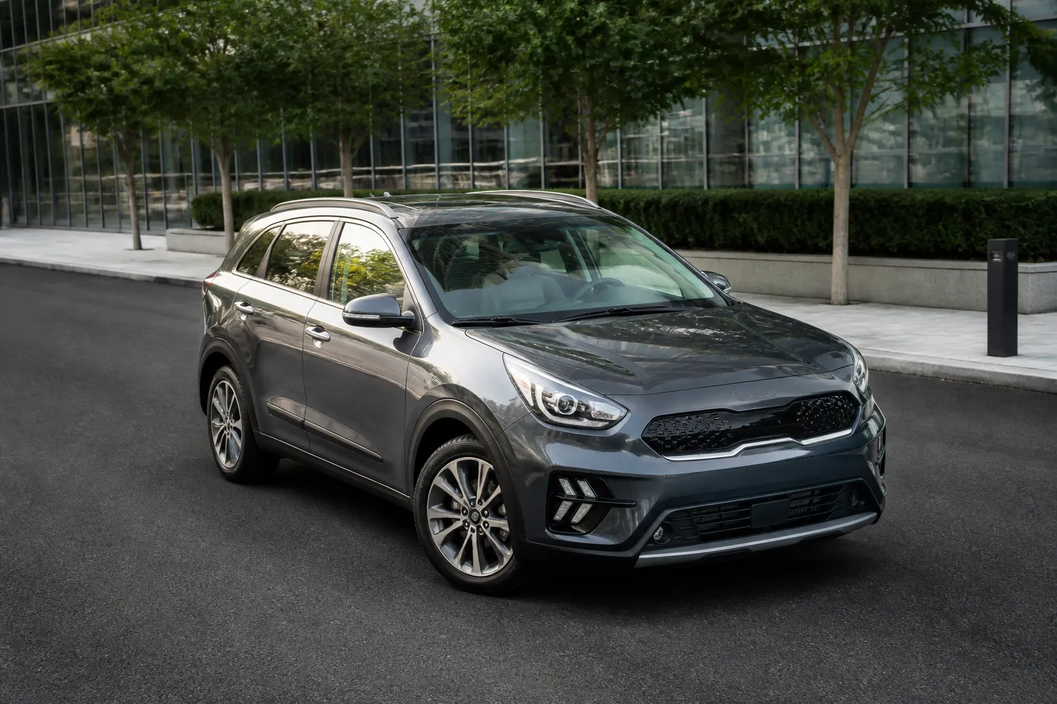 Kia Niro Hybrid на городской дороге, вид спереди сбоку. Через стеклянный люк виден светлый салон автомобиля.