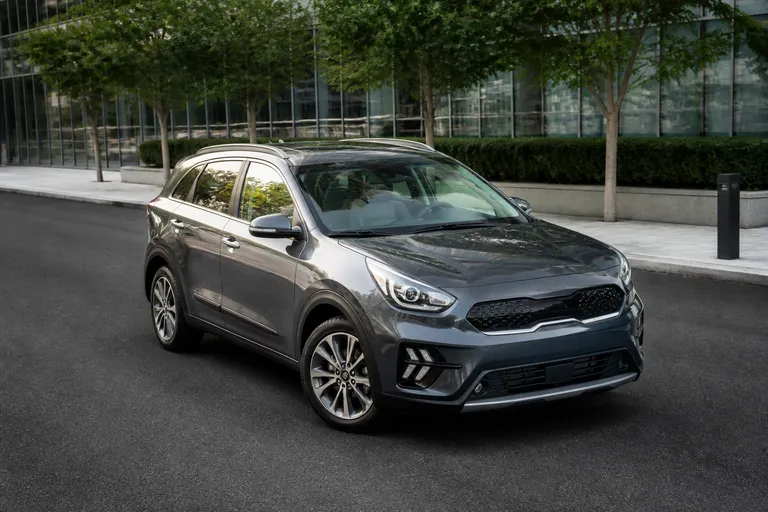 Kia Niro Hybrid на городской дороге, вид спереди сбоку. Через стеклянный люк виден светлый салон автомобиля.