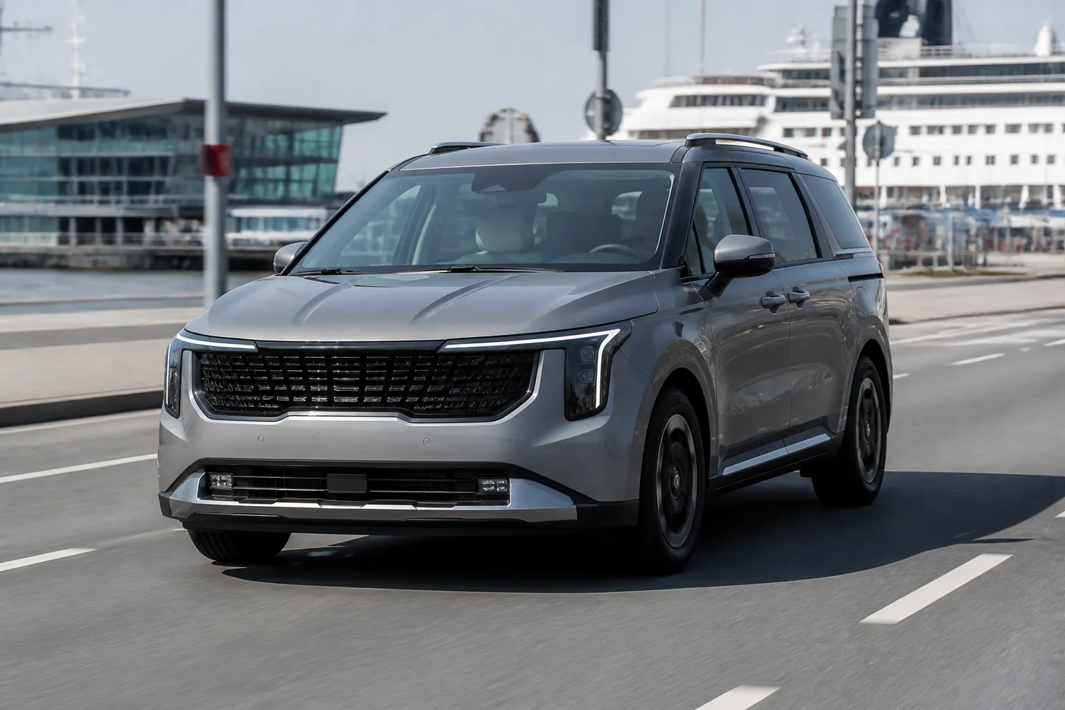 Kia Carnival на городской дороге, рядом виден современный портовый терминал. Сцена передаёт тему покупки и доставки автомобиля из Кореи.