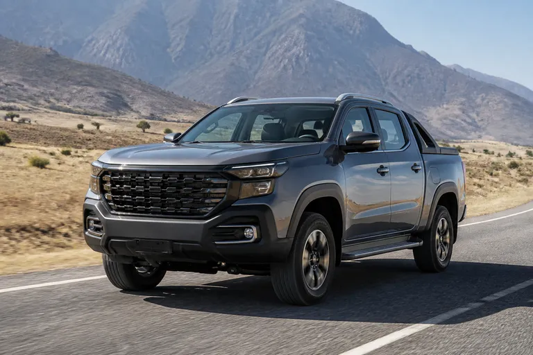 Новый пикап Changan Hunter на дороге за городом, рядом видны горы и сухая грунтовая обочина. Машина снята в реалистичном ракурсе спереди сбоку.