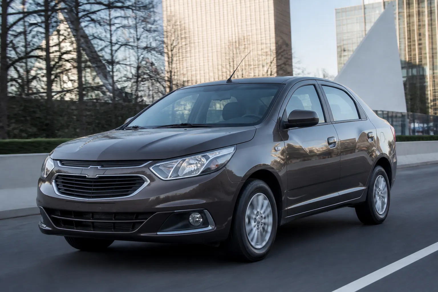 Новый Chevrolet Cobalt на городской дороге, снятый спереди под небольшим углом. На фоне видны современные здания и дневное естественное освещение.