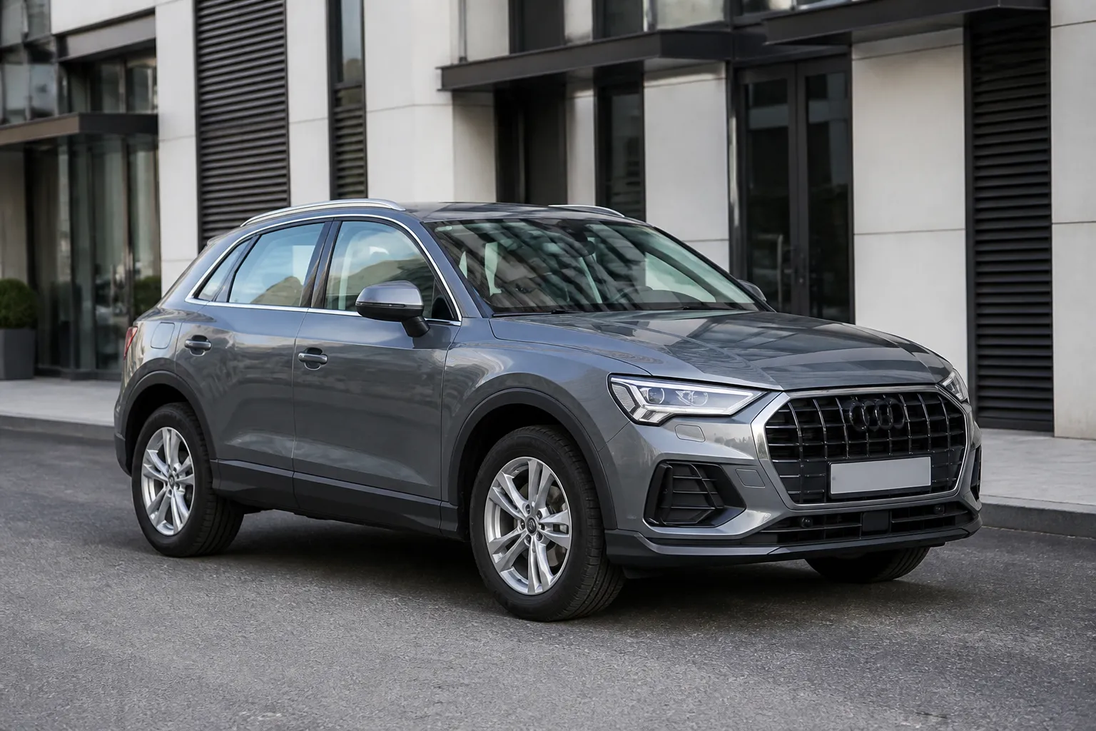 Audi Q3 стоит на городской улице перед тест-драйвом. Автомобиль снят спереди сбоку в естественном дневном свете.