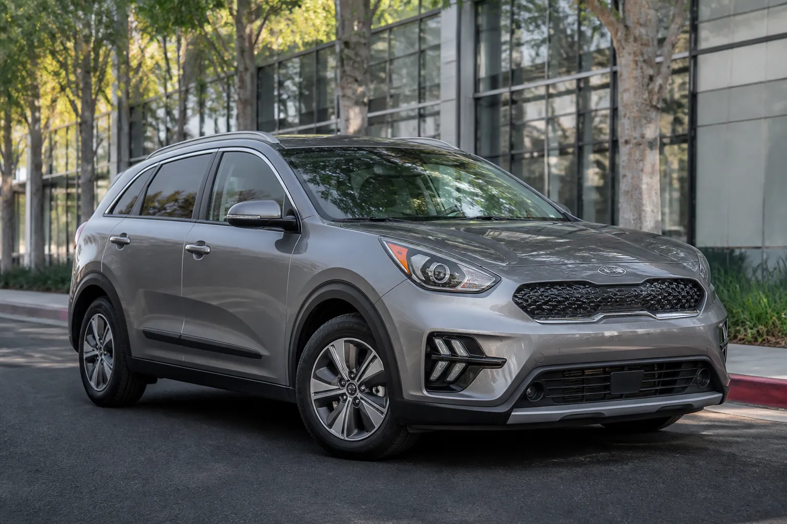 Kia Niro на городской улице перед выездом на осмотр автомобиля. На фоне видны современные дома и мягкий дневной свет.