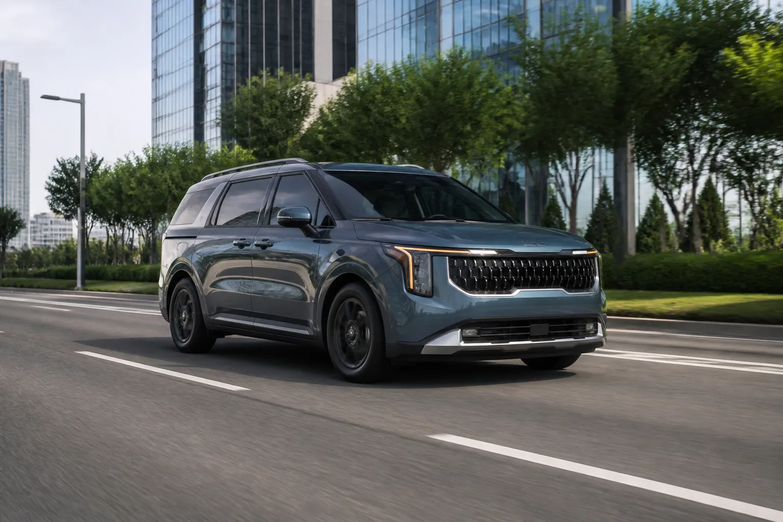 На обложке крупный минивэн KIA Carnival на городской дороге, снятый спереди под углом. Автомобиль выглядит как семейная машина для поездок по городу и трассе.