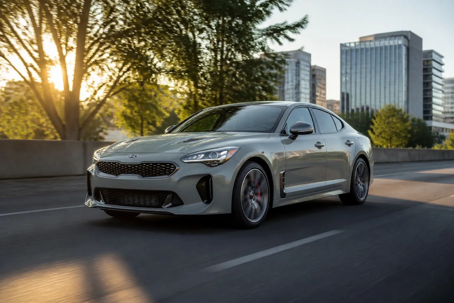 KIA Stinger на городской дороге в вечернем свете, автомобиль снят спереди под углом. Сцена подчёркивает формат спортивного лифтбека для города и трассы.