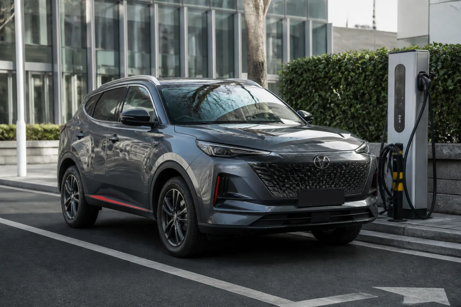 Changan Q05 на городской дороге возле современной зарядной станции. Автомобиль снят спереди под углом в естественном дневном свете.