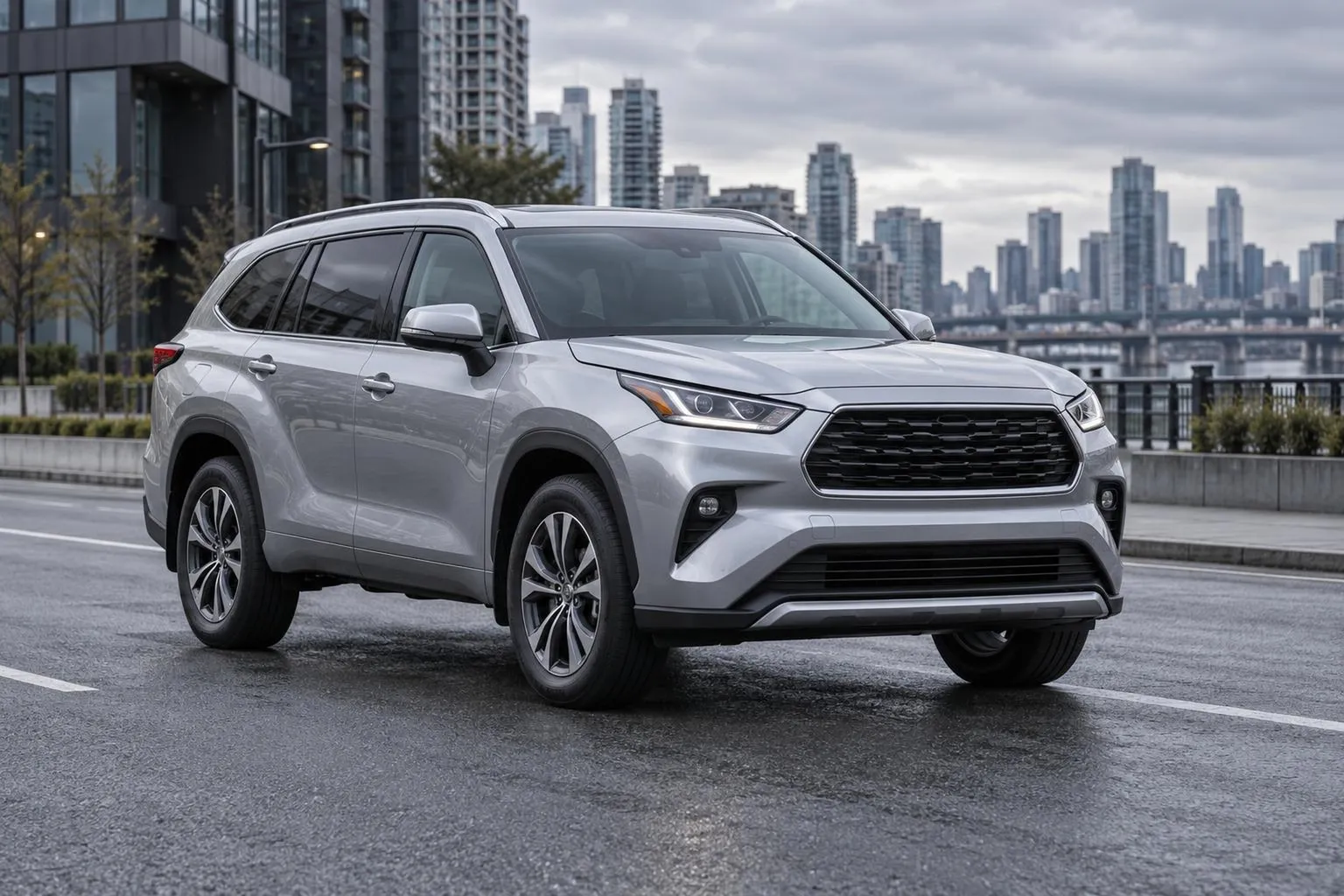 Toyota Highlander стоит на городской дороге в пасмурный день. Крупный семейный SUV показан спереди под углом, без логотипов и текста.